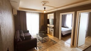Een moderne hotelkamer met een bank, een klein tafeltje, een televisie en een bed.