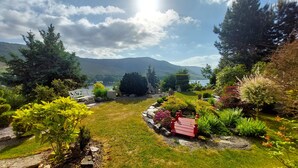 A garden with a bench, a small pond, and a mountain in the background. - Apartment Märchenhain with beautiful view (Niederheimbach)