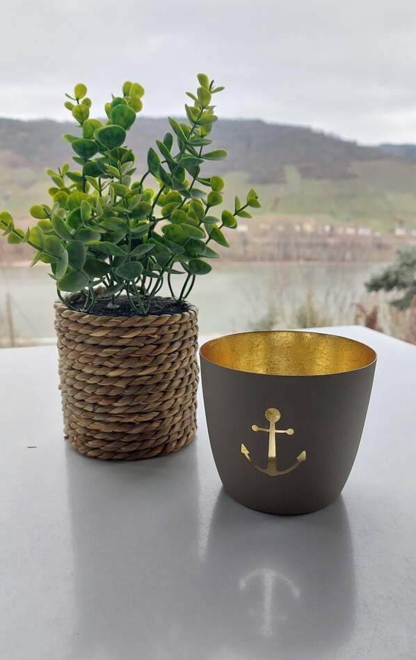 Una maceta tejida y un cuenco oscuro con un diseño de ancla dorada sobre una mesa.