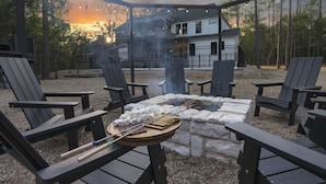 Zona d'estar a l'aire lliure amb cadires Adirondack, una xemeneia i una barbacoa amb torrons i xocolata.