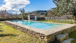 Ein rechteckiger Pool mit Steinwänden, umgeben von einer Mauer und einem Holzzaun.