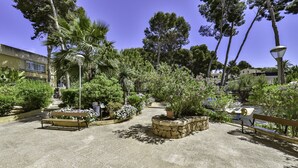 A paved courtyard with benches, stone planters, and a variety of trees and shrubs. - Apartment Sunset Moraira City (Moraira)