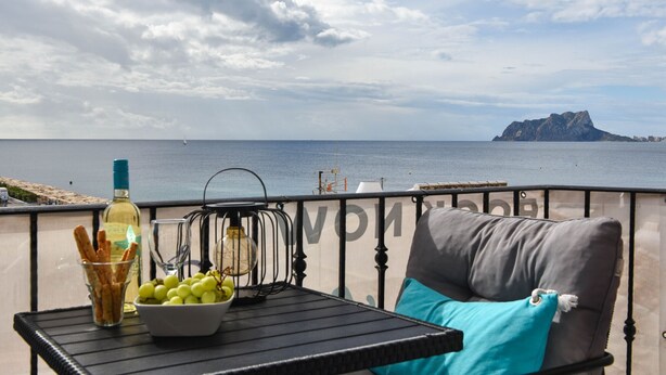 A balcony with a table, a bottle, and a bowl of grapes. - Apartment Octopus Moraira (Moraira)
