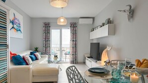 A modern living room with a sofa, a glass dining table, and a TV. - Apartment Octopus Moraira (Moraira)