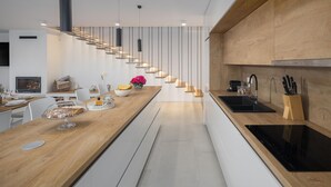 A modern kitchen with a wooden countertop, a built-in oven, and a sink with a knife block. - Amazing home in Rapavel with sauna (Rapavel)