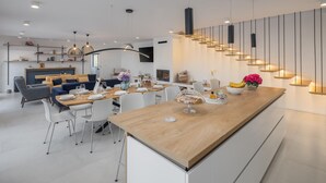 A modern kitchen with a central island, white cabinetry, and a dining area with a sofa and chairs. - Amazing home in Rapavel with sauna (Rapavel)