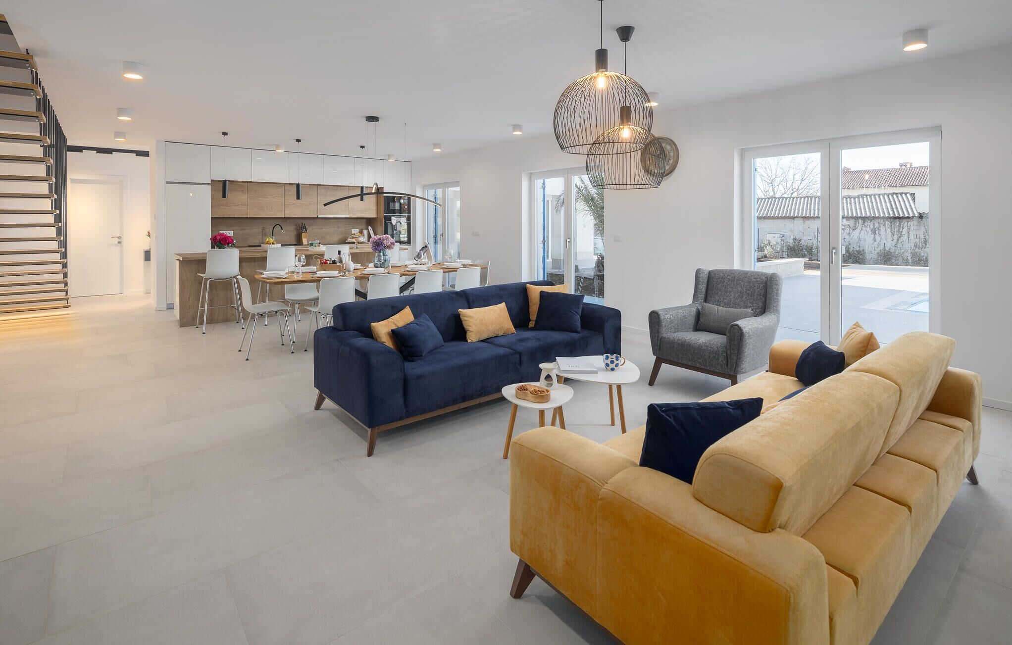 A modern living room with a sofa, armchairs, and a dining area.