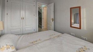 A bedroom with a bed, a wardrobe, a mirror, and a door leading to another room. - Awesome home in Rota with WiFi (Rota)
