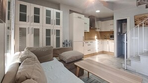 A modern living room with a sofa, a coffee table, and a kitchen area with cabinets and a sink. - Awesome home in Rota with WiFi (Rota)