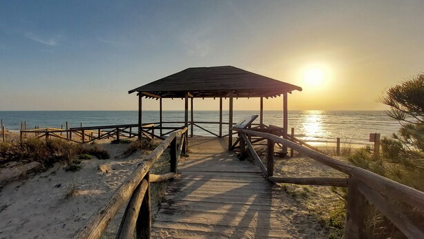 A wooden pier leading to a beach hut with a view of the ocean at sunset. - Awesome home in Rota with WiFi (Rota)