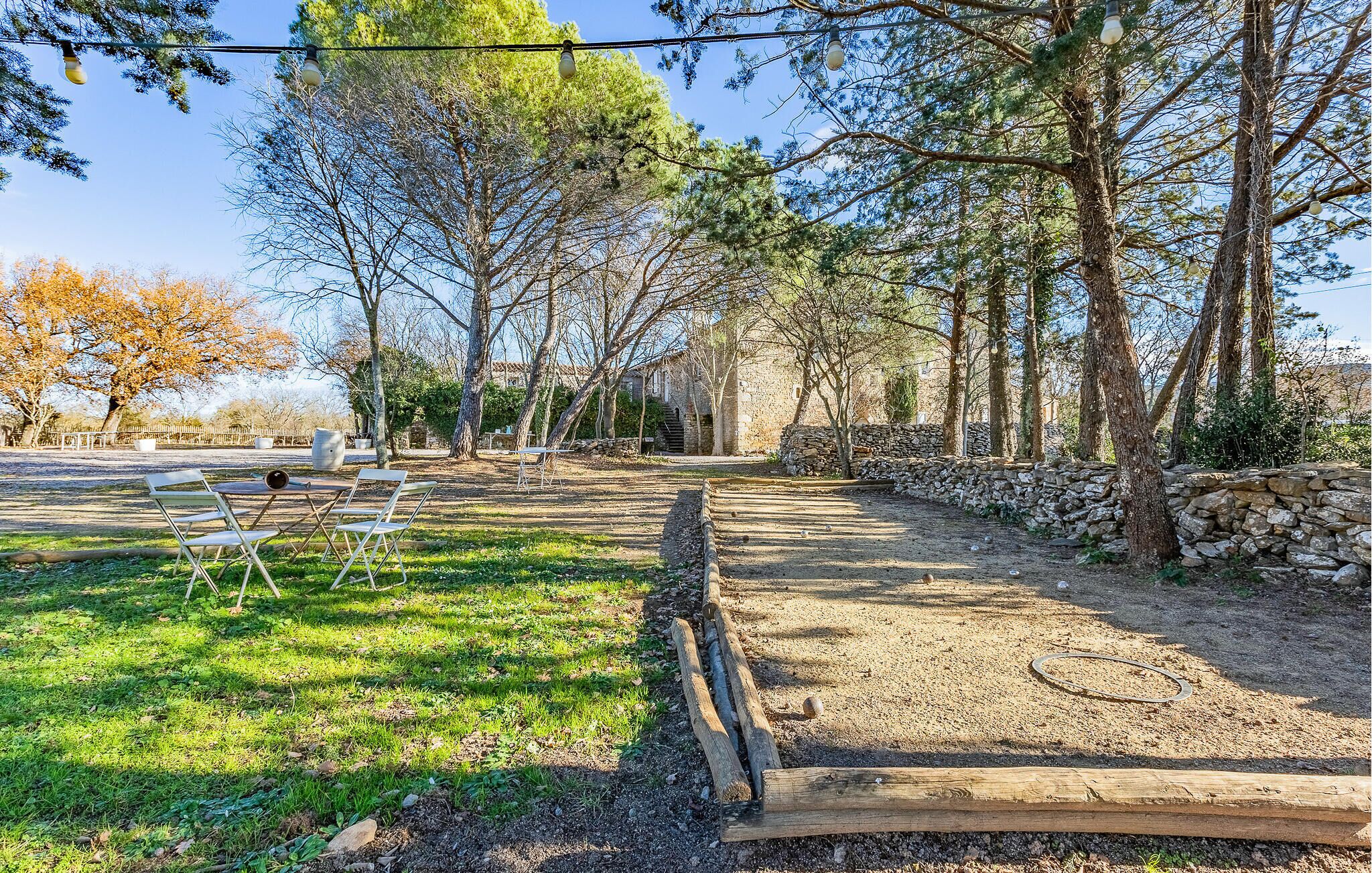 Un espace extérieur avec un sentier de terre, des bancs en bois et des murs en pierre.