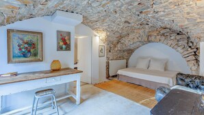 A rustic room with a stone wall, a bed with white bedding, a desk with a chair, and artwork on the walls. - Nice home in LE ROUET with house a panoramic view (LE ROUET)