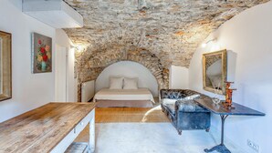A bedroom with a stone ceiling, a bed, a wooden table, and a mirror. - Nice home in LE ROUET with house a panoramic view (LE ROUET)