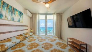 A hotel room with a bed, a ceiling fan, a TV, and a balcony with a view of the sea. - Cozy BEACH FRONT 1BR w/Pool & PK @Luquillo Beach (Luquillo)