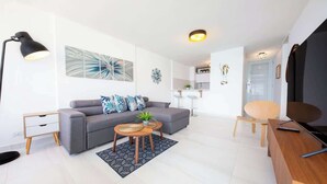 A modern living room with a grey sofa, two side tables, a coffee table, and a TV stand. - Cozy BEACH FRONT 1BR w/Pool & PK @Luquillo Beach (Luquillo)