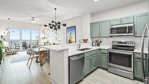 A modern kitchen with green cabinets, stainless steel appliances, and a large island.