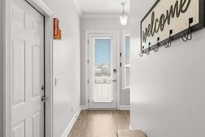 Enter a warm and inviting space with a welcoming door and a cozy bench at the end of the hallway.