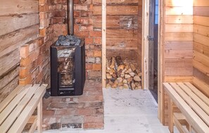 Une cabane en bois rustique, dotée d’une cheminée, d’un banc et d’une pile de bois de chauffage.