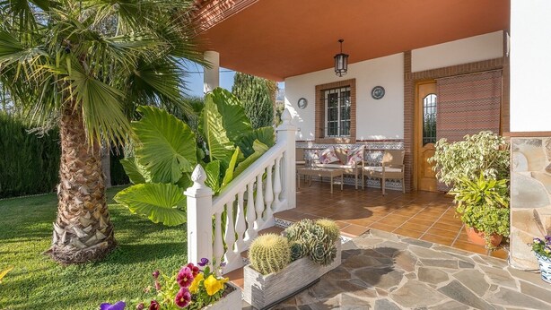 A covered patio with a stone floor, a white railing, and a seating area with a table and chairs. - Las Cuatro Flores Órgiva by Ruralidays (Granada)