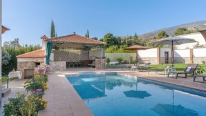 A swimming pool with lounge chairs and a covered patio area. - Las Cuatro Flores Órgiva by Ruralidays (Granada)
