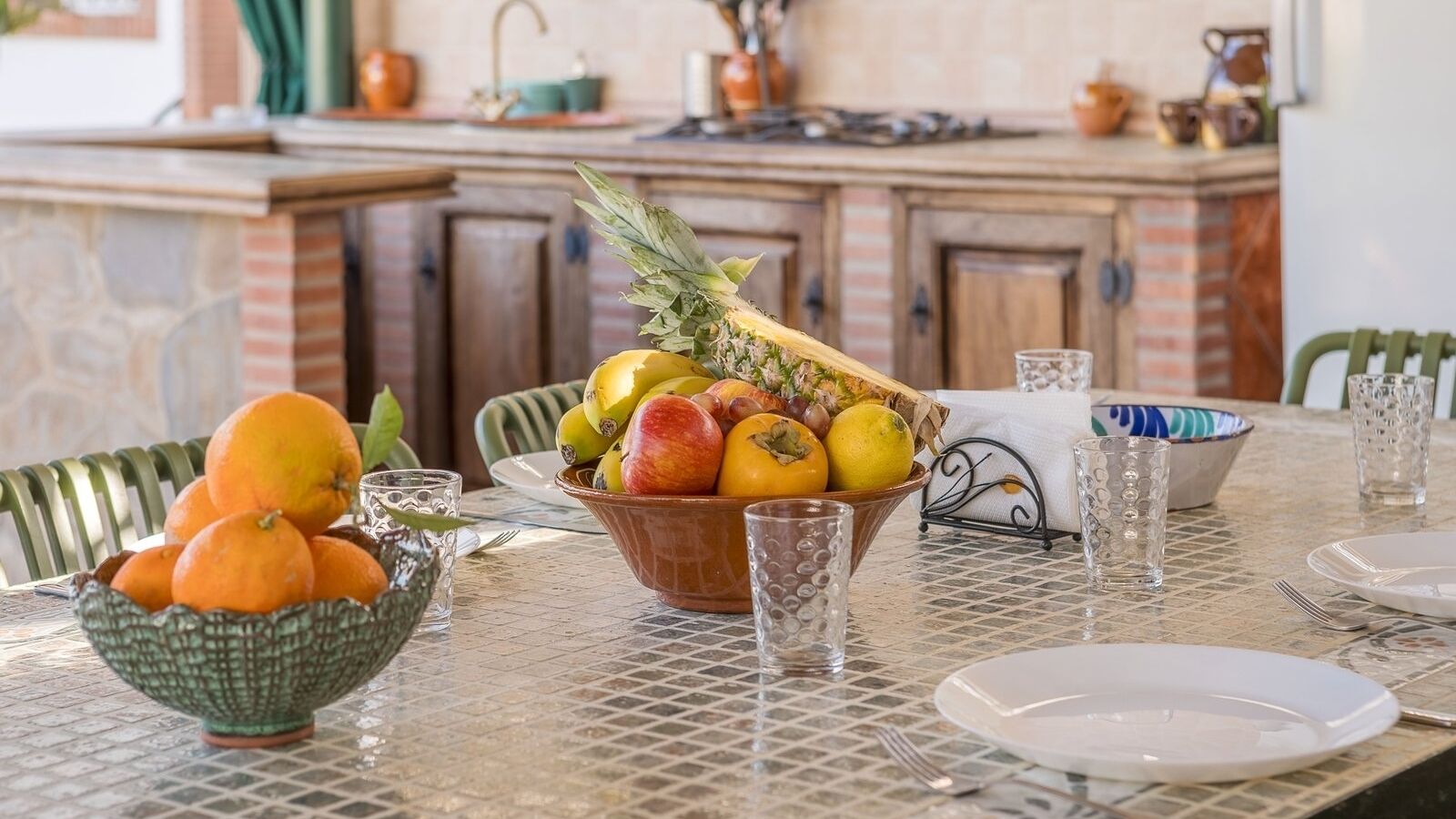 Taula de dinar amb un plat de fruita, un bol d'albercocs i un mantell estampat.