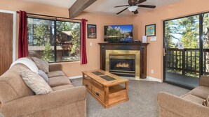A living room with a fireplace, large windows, and a ceiling fan. - Inside Yosemite Park 3BR Sleeps 8 Game Loft (Yosemite Valley)