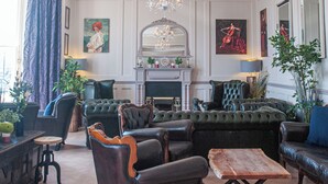 Ein geräumiges Wohnzimmer mit einer Chandelier, Ledersofas, einem Kamin und Kunstwerken an den Wänden.