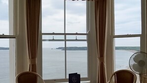 Ein Hotelzimmer mit einem Bett, zwei Stühlen, einem Tisch und Meerblick.