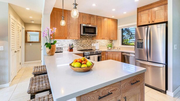 Una cocina moderna con armarios de madera, electrodomésticos de acero inoxidable y una isla central con frutero.