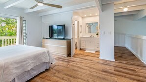 Een slaapkamer met een bed, een televisie en een houten vloer.