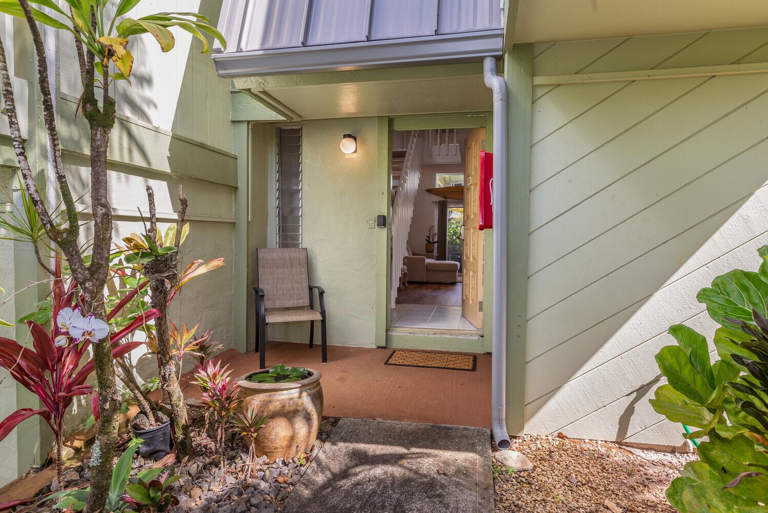 A house with a covered porch, a chair, and a potted plant.