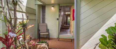 A house with a covered porch, a chair, and a potted plant.