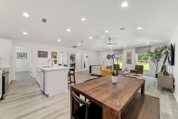 Una cocina moderna con armarios blancos, una mesa de comedor de madera y un ventilador de techo.