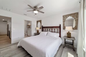 Cozy retreat with a large bed, ceiling fan, and a bedside table with a lamp.