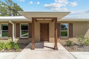 A house with a covered entryway, a front door, and two windows with shutters. - Crownwood Country New 3bd 2ba near WEC equestrian, FAST Swimming, GOLF (Ocala)