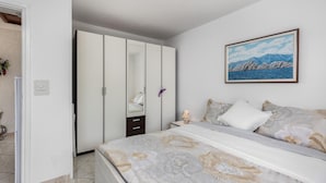 A bedroom with a bed, a wardrobe, and a painting on the wall.
