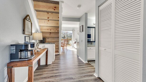 A kitchen with a coffee machine, wooden paneling, and a view to the dining area. - Home of Light, Branson, Mo (Branson)