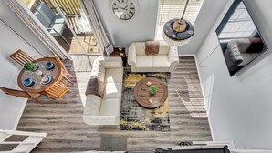 A modern living room with a white sofa, a round coffee table, and a dining area with a wooden table and chairs. - Home of Light, Branson, Mo (Branson)