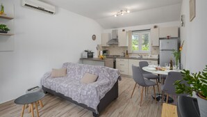 A compact living space with a sofa, dining table, chairs, kitchen area, and a small side table.