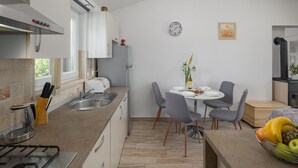 A modern kitchen with a gas stove, a sink, and a dining area with a table and chairs.