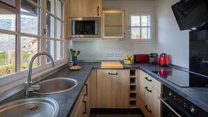 A modern kitchen with wooden cabinets, a stainless steel sink, a microwave, a toaster, and a refrigerator. - Chalet Jornata - cosy stay 10p for families with games room - OVO Network (Morillon)
