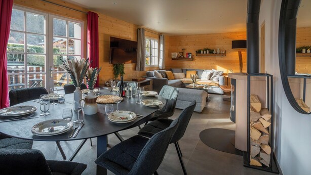 A modern living room with a sofa, a dining table set for four, and a fireplace. - Chalet Jornata - cosy stay 10p for families with games room - OVO Network (Morillon)