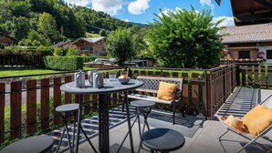 A terrace with a table set for two, surrounded by wooden chairs and a cushioned bench. - Chalet Jornata - cosy stay 10p for families with games room - OVO Network (Morillon)