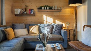 A cozy living room with a wooden wall, a sofa, a coffee table, and a lamp. - Chalet Jornata - cosy stay 10p for families with games room - OVO Network (Morillon)