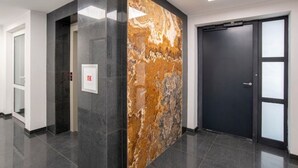Ein moderner Korridor mit Marmorwand, einer Tür und einem Aufzug.