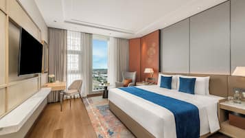 Habitación de hotel moderna con una cama grande, un escritorio, una silla, un televisor y vistas a la ciudad.