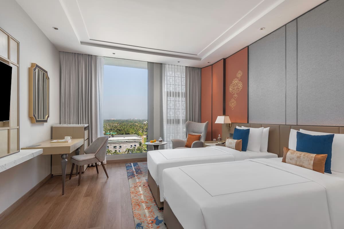Une chambre d’hôtel avec deux lits, un bureau, une chaise, une télévision et une vue sur la ville.