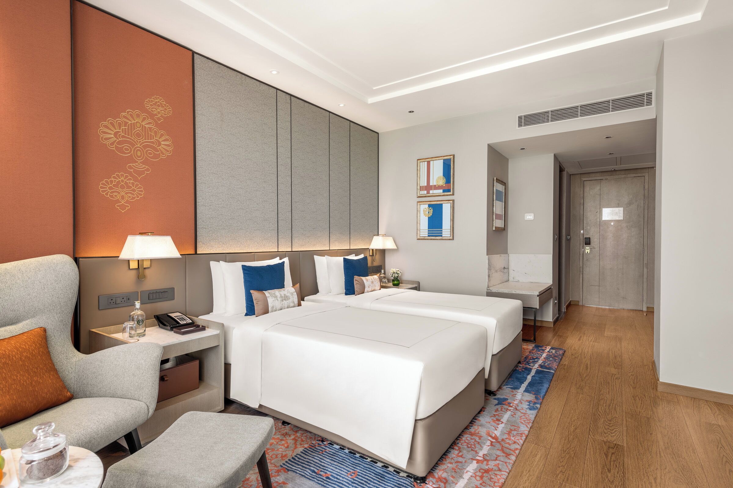 Une chambre d’hôtel avec un grand lit, un bureau, une chaise et une petite table avec une lampe.