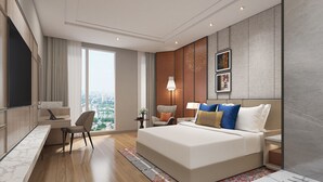 Une chambre d’hôtel moderne dotée d’un grand lit, d’un bureau avec un ordinateur portable, d’une chaise, d’une table de chevet avec une lampe et offrant une vue sur la ville grâce à de grandes fenêtres.