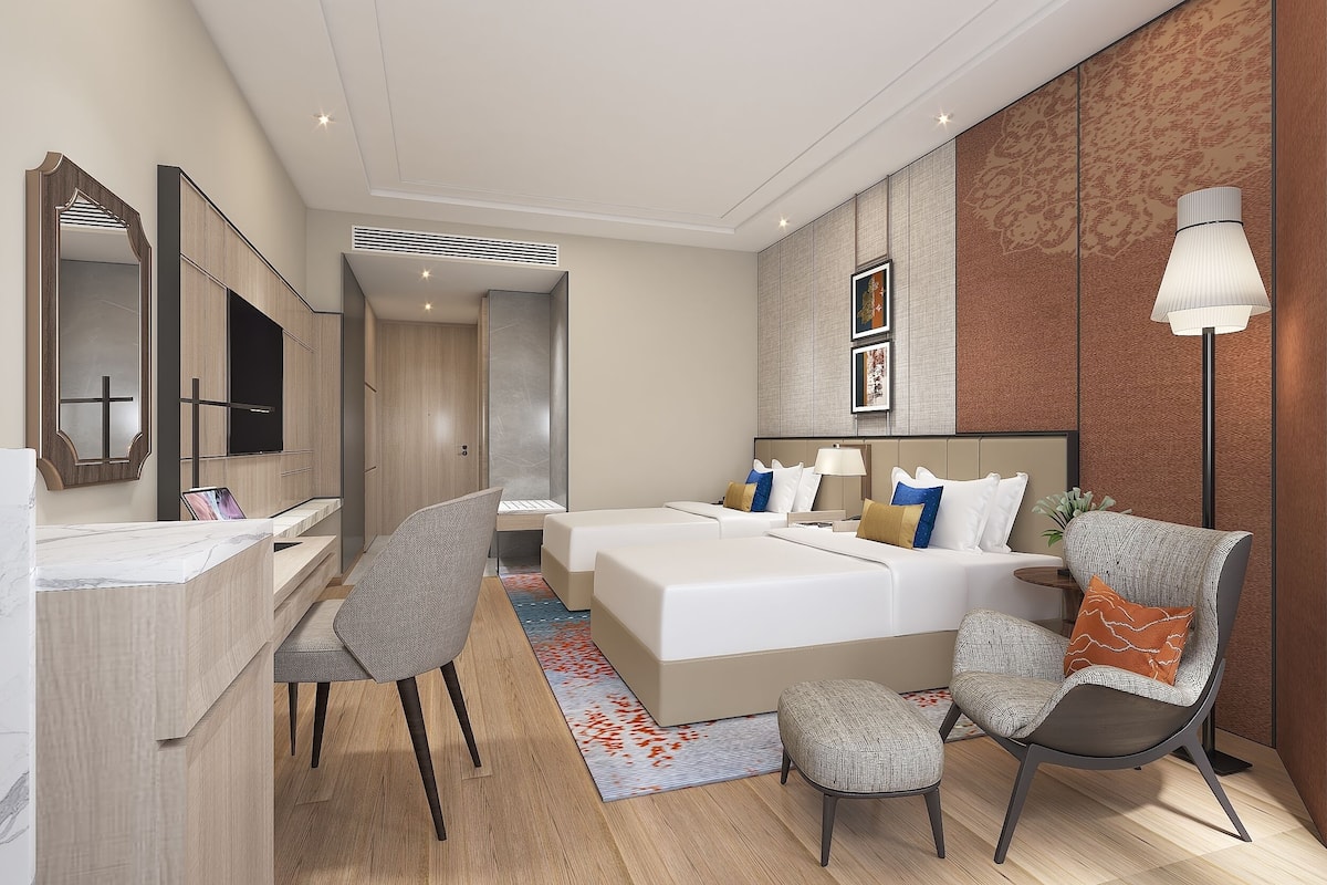 Une chambre d’hôtel moderne équipée d’un lit, d’un bureau, d’une chaise et d’une lampe.